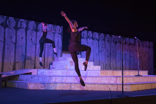 Two ballet dancers performing on a purple lit stage.
